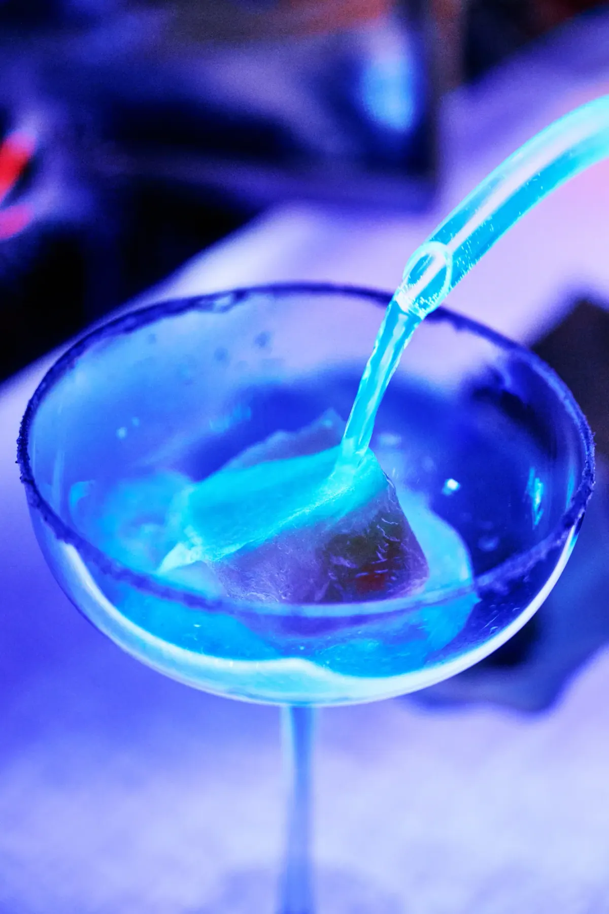 A blue cocktail poured into a sugar rimmed glass