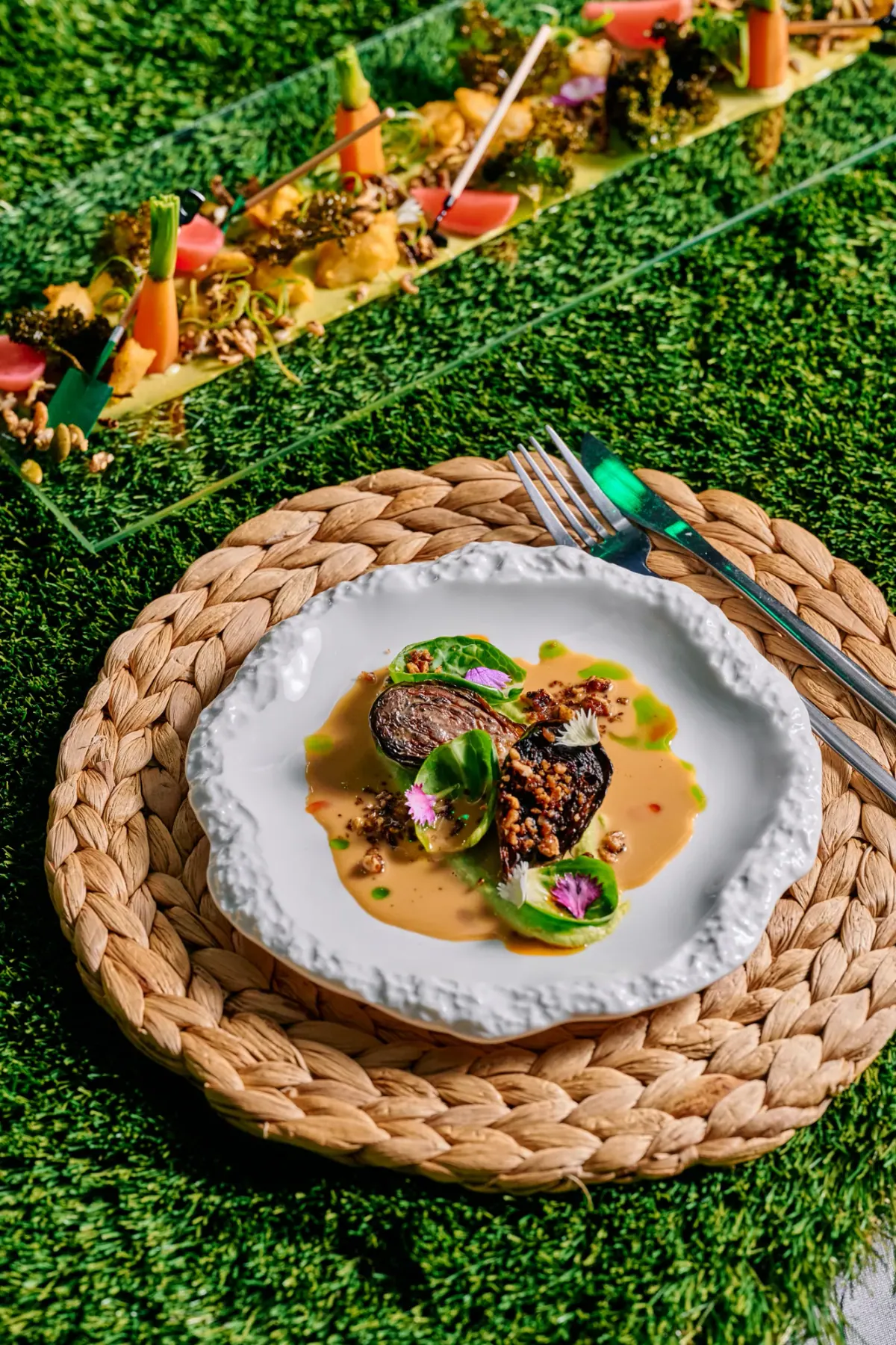 A plated course with sauce and herbs on a white plate and a woven placemat