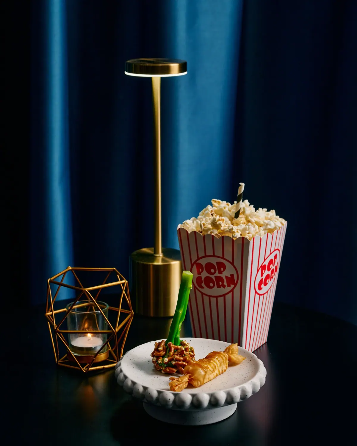 A popcorn box beside a gold lamp on the table under blue light
