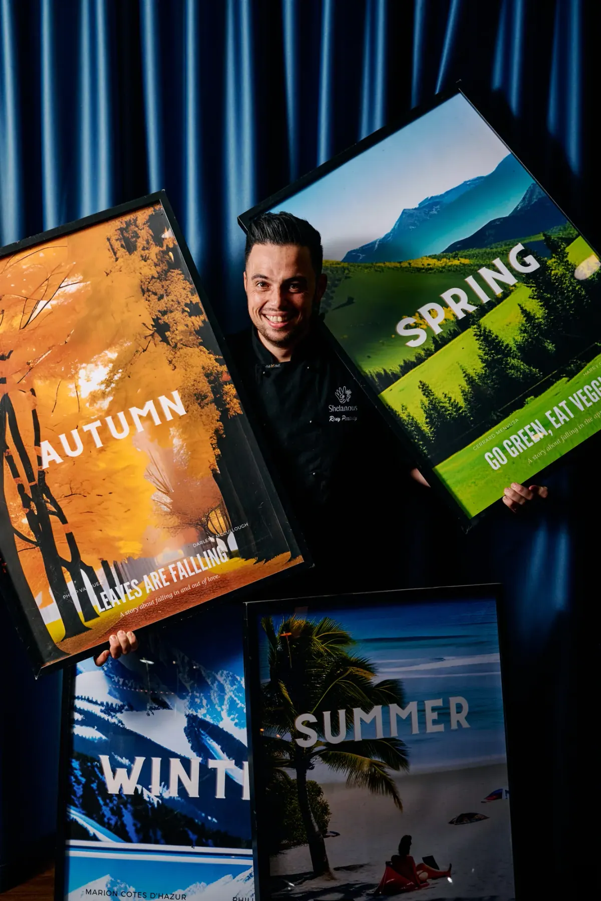 Chef Rony holding the four season posters in front of the blue curtain